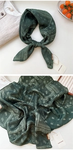 Détail macro d'un foulard en soie cachemire vert foncé avec motifs blancs et bords fins