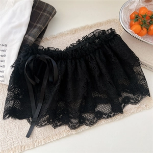 Détail d'une jupe en dentelle noire avec nœud décoratif en ruban et bords festonnés