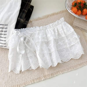 Détail de la mini-jupe en dentelle florale blanche à trois couches avec rubans en satin
