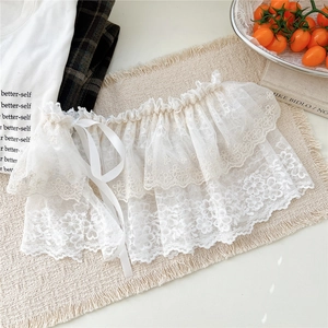 Détail de la bordure en dentelle blanche avec broderie florale et ruban en satin