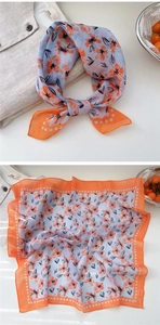 Detail showing orange floral print on light blue cotton linen scarf and fabric texture