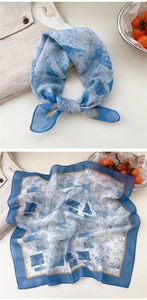 Detail view of light blue square scarf with white floral patterns and dark navy border