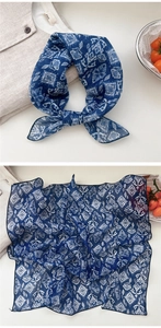 Detail of blue geometric print cotton linen scarf tied as a bow on a white linen shirt