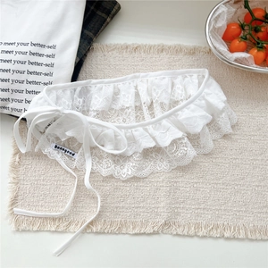 Close-up of white floral lace trim detailing with branded label on beige textile