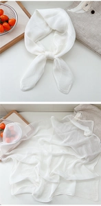 Detail of white silk scarf with stitched edges draped over a linen shirt background