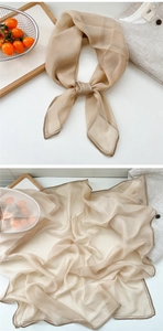 Macro view showing champagne silk scarf texture with delicate rolled edges and sheer fabric