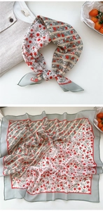 Detail of floral silk scarf showing berry prints and lightweight smooth texture in flat lay