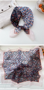 Detailed macro view showing floral silk scarf patterns and exquisite rolled edge finish