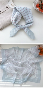 Detail view of light blue silk floral square scarf featuring red geometric diamond patterns