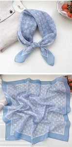 Detail of light blue floral square scarf showing texture and decorative bow knot style
