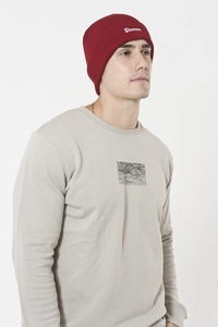 Detail of burgundy knit beanie with white embroidery worn by a male model outdoors