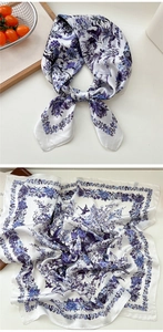 Close-up of silk scarf with purple floral and bird print on a white satin base