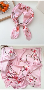 Detailed close-up of pink floral silk scarf with cherry blossom pattern and satin texture