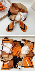 Detail showing the geometric color block pattern and silk texture of the square scarf