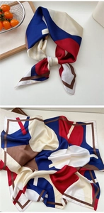 Macro shot of satin silk scarf featuring geometric red and navy blue patchwork pattern