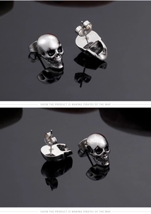 Macro detail of men's skull stud earrings in polished silver steel with butterfly backs