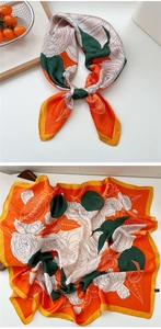 Detailed close-up of floral silk scarf with orange camellia print on a wooden tray