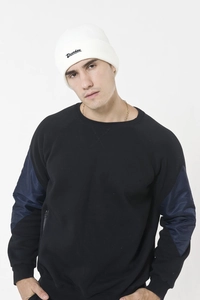 Detail of white ribbed beanie with black Drunken embroidery worn with black sweatshirt