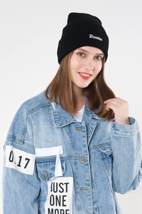 Close-up of Drunken script embroidery on black knit beanie with denim jacket details