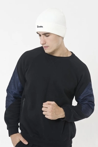 Close-up of white knitted beanie featuring black Drunken embroidery and ribbed texture