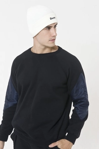 Detail of white knit beanie with black script embroidery and ribbed texture finish