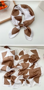 Detail view of floral silk scarf featuring brown and white geometric patterns on satin