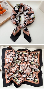 Detailed close-up of floral silk scarf with black borders and pink petals on white