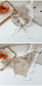 Detail of vintage brown lace triangle scarf with white floral embroidery on beige desk