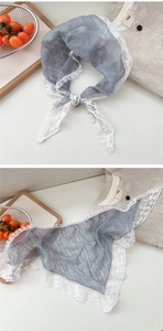 Detail of light blue lace scarf featuring delicate white floral embroidery and sheer fabric