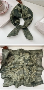 Detailed close-up of dark green paisley silk scarf with vintage patterns and textures