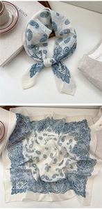 Detailed view of cream silk scarf with blue paisley pattern and neat hemmed edges