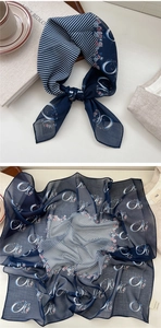 Close-up of navy blue floral silk scarf with geometric stripes and C-pattern detail
