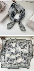 Close-up of floral square silk scarf with green and white patterns and delicate edge seams