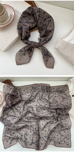 Detail of elegant brown silk scarf with black rose patterns tied in a stylish bow knot