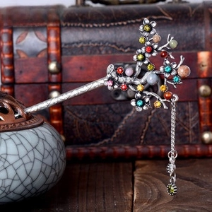 Macro detail of retro plum blossom hair stick with colorful crystals and metal tassels
