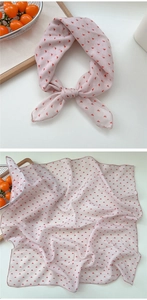 Detail view of pink cotton linen square scarf with red triangle patterns and fine hemmed edges