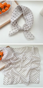 Close-up of white linen square scarf with black triangle print in a natural lifestyle setting