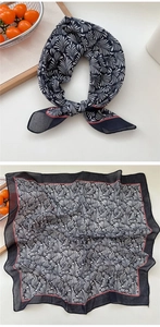 Detail of a square silk scarf with black and white scallop patterns and a red border