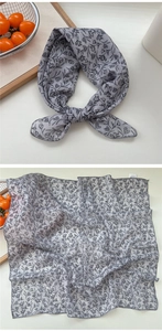 Close-up detail of grey floral print silk scarf showing fabric texture and edge stitching