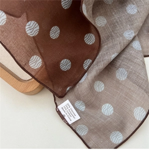 Detail eines Punkteschals mit Leinentextur und Waschetikett mit Materialzusammensetzung