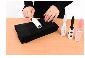 Manual lint roller cleaning black clothes on wood desk with stylish patterned refills