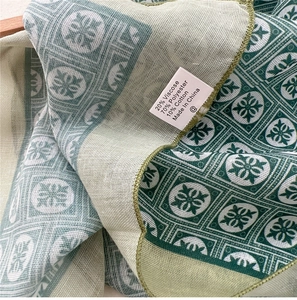 Detail showing the fabric texture and wash label of the green floral cotton linen scarf