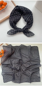 Detail of silk-like neckerchief with green oval geometric pattern on black fabric