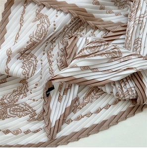 Detailaufnahme des Paisley-Musters auf dem Plissee-Seidenschal mit Pflegeetikett