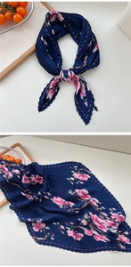 Detail eines dunkelblauen Plissee-Halstuchs mit rosa Blumenmuster und Textur