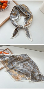 Detail des plissierten Seidenquadrats mit orange-grauem Muster auf einem Holztablett