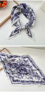 Detail eines plissierten Seidenschals mit blauem Vogelprint und feiner Textur