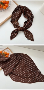 Detail eines kaffeebraunen plissierten Seidenschals mit weißen Punkten und Textur