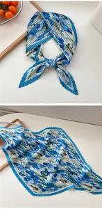 Detail eines blauen Plissee-Halstuchs mit Blumenmuster und eleganter Knotentechnik