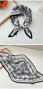 Makrodetail eines plissierten weißen Schals mit Paisleymuster und gewelltem Saum
